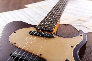 Sticker - Electric guitar with music notes on wooden table close up