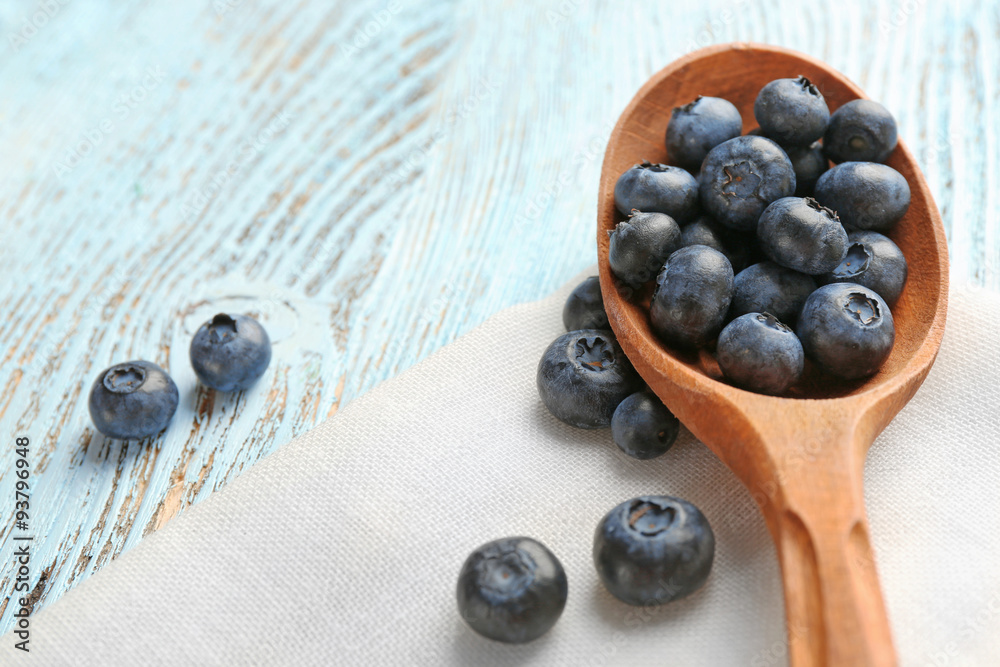 Fresh blueberries in spoon on wooden table close up