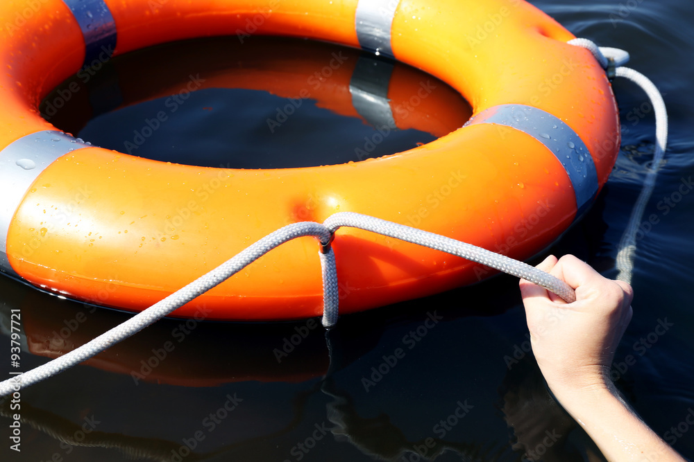 Hand holds a cord of a life buoy
