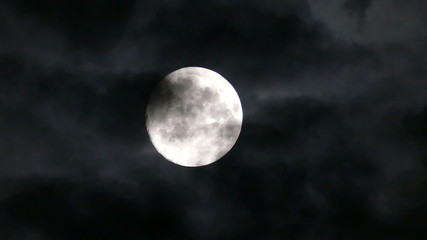 full moon moving between clouds