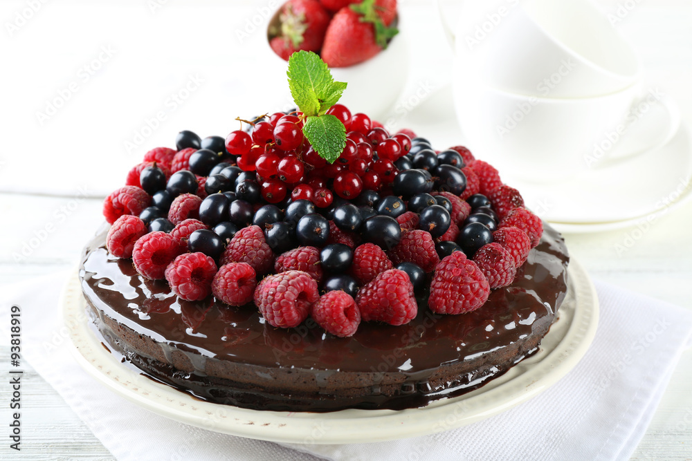 Delicious chocolate cake with summer berries on wooden table, closeup