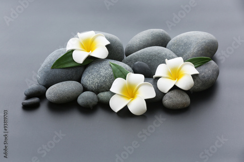 Fototapeta na wymiar Spa stones with flowers on gray background