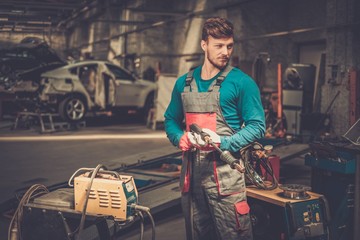 Poster - Mechanic with welding machine in a workshop