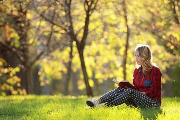 Wall Mural - girl in a sunny park reading a book