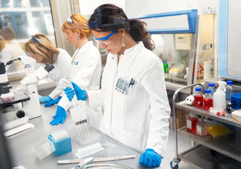 photo of three real female scientists researching in laboratory. photo taken behind the glass.