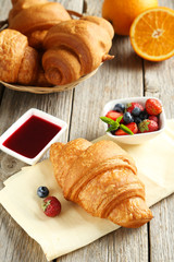 Wall Mural - Fresh tasty croissants with berries on grey wooden background