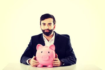 Businessman with piggybank by a desk.