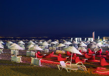 Beds And Straw Umbrellas On A Beach At Night