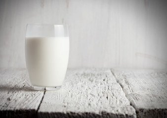 Glass of milk standing on old wooden table