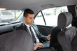 © bokan - Businessman using laptop while commuting to work by taxi
