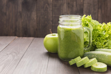 Healthy green vegetables and green fruit smoothie on rustic wood