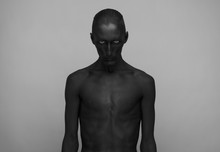 Gothic And Halloween Theme: A Man With Black Skin Is Isolated On A Gray Background In The Studio, The Black Death Body Art