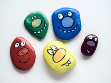 Five Smiling Faces Of Monsters. Painted Acrylic Pebbles.