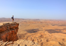 Magic Desert Landscape / View Of Negev Stone Desert.Traveler On A Cliff In The  National Geological Park HaMakhtesh HaGadol,Large Crater - Geological Erosion Land Form, Israel 