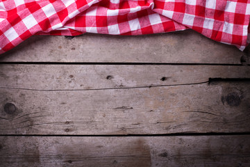 Canvas Print - Red  checkered kitchen towel  on vintage  wooden background.