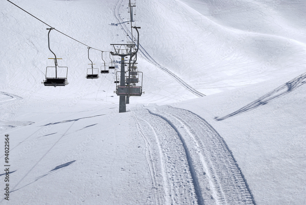 Wyciąg krzesełkowy i ślady ratraka (snowgroomer) w śniegu na przełęczy Presena, Passo Tonale - obrazy, fototapety, plakaty 
