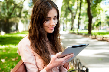 young caucasian female student with tablet on campus