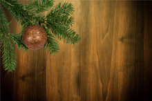 Green Branch With Christmas Ball On Wooden Background