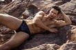 Handsome man in underwear lying on the rocks