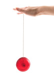 Fototapeta Natura - A hand holding a red yoyo as it goes up and down, isolated on white.