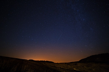 the starry sky and milky way above the lighted lanterns city.