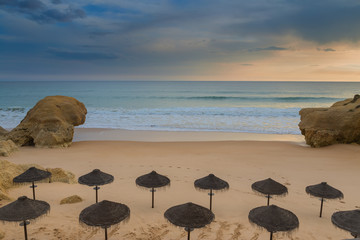 Wall Mural - Dramatic views of the beach with umbrellas for the sun. Before the rain.