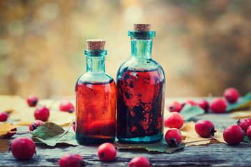 Wall Mural - tincture bottles of hawthorn berries and red thorn apples on woo