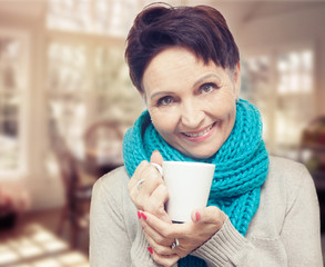 Wall Mural - 50 years old attractive woman with a white cup of tea in hand