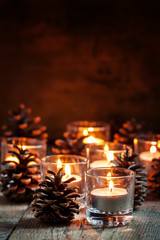 Wall Mural - Christmas Christmas card with glowing small candle and fir cones