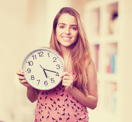 young cute woman smiling and holding a clock on white