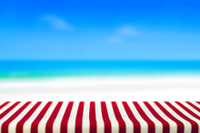 Table Covered With Striped Tablecloth On Blurred Beach Backgroun