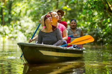 a group of tourists on a boat tour through the lush amazon rainforest, surrounded by exotic wildlife