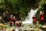A group of adventurous people having fun zip-lining through a canyon in Ecuador, surrounded by waterfalls and enjoying the thrilling adventure.