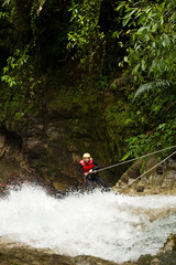 Wall Mural - Experience the thrill of adventure as you witness an adult woman clad in waterproof gear descending a majestic waterfall.