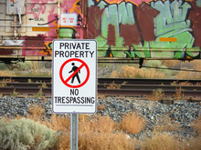 Private Property No Trespassing Sign With Graffiti Covered Train In Background