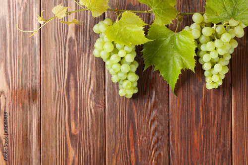 Obraz w ramie Bunch of white grapes with leaves on wood