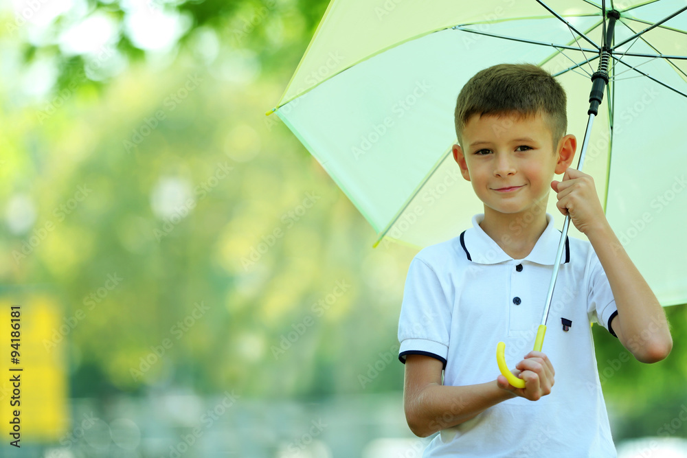 Boy under big creamy umbrella at the park