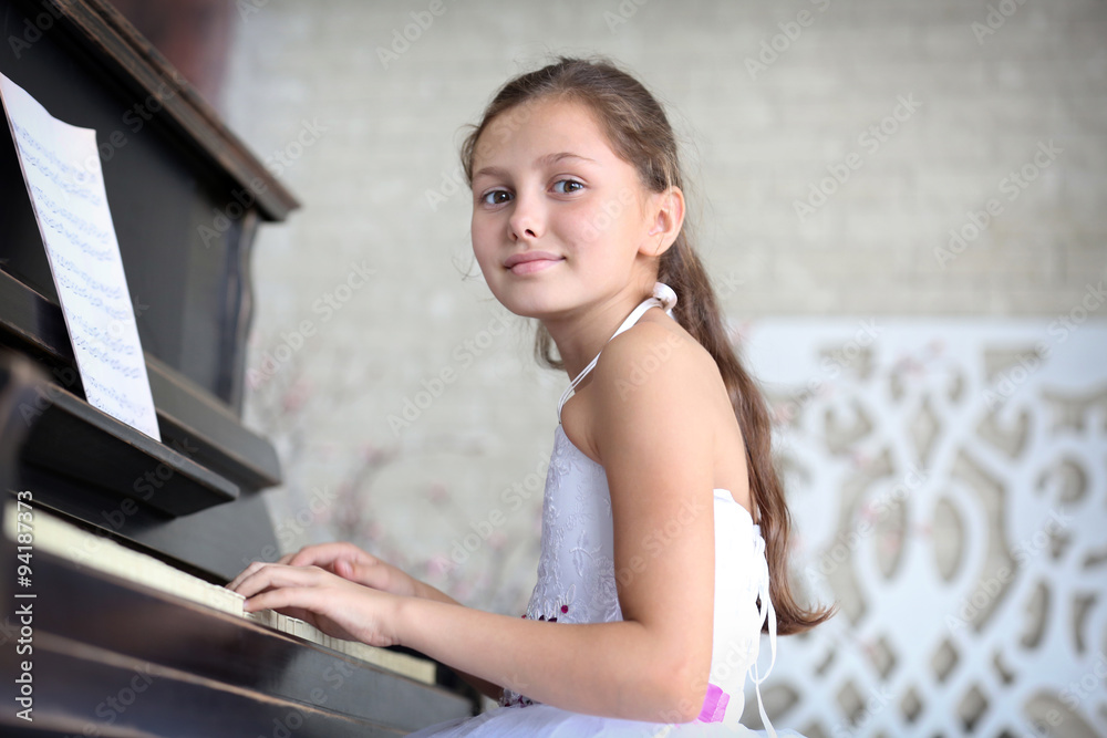 Attractive little princess girl plays piano