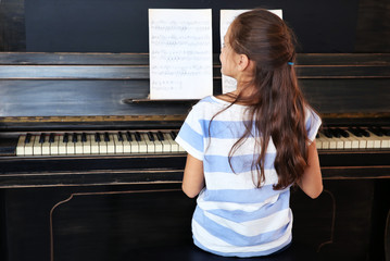 Poster - Cute little musician girl plays piano, back view