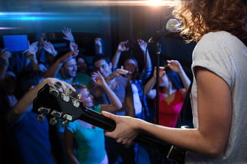 female singer playing guitar over happy fans crowd