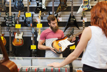 Assistant Showing Customer Guitar At Music Store