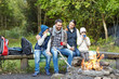 © Syda Productions - happy family sitting on bench at camp fire