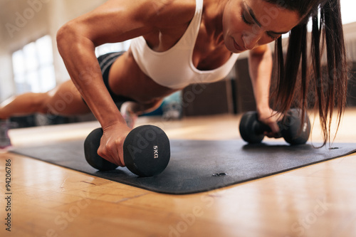 Fotografia Muscular woman doing push-ups on dumbbells