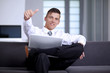 © COSPV - Young businessman showing hand gesture thumb up success sign sit