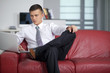 © COSPV - Happy businessman working with a notebook and sitting on couch i