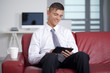 © COSPV - Happy young businessman with tablet at sofa in office sitting on