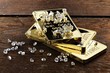 Goldbarren und geschliffene Diamanten auf rustikalem Holzhintergrund