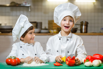 Funny happy chef boys cooking at restaurant kitchen