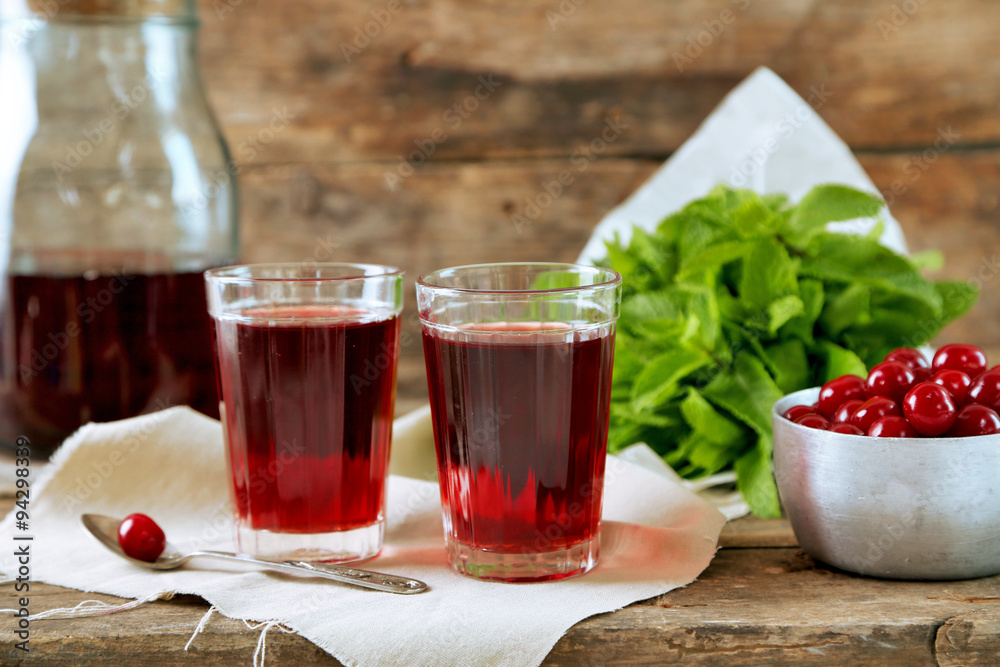 Sweet homemade cherry juice on table, on wooden background