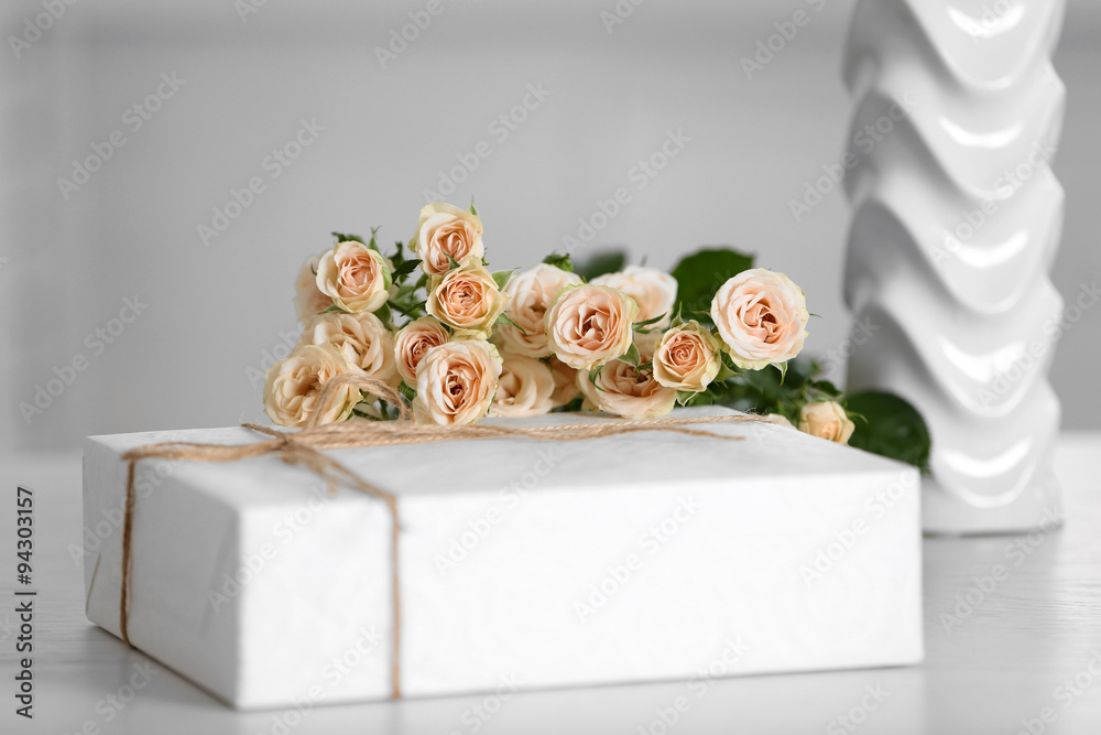 Big white gift box with bouquet of roses on the table